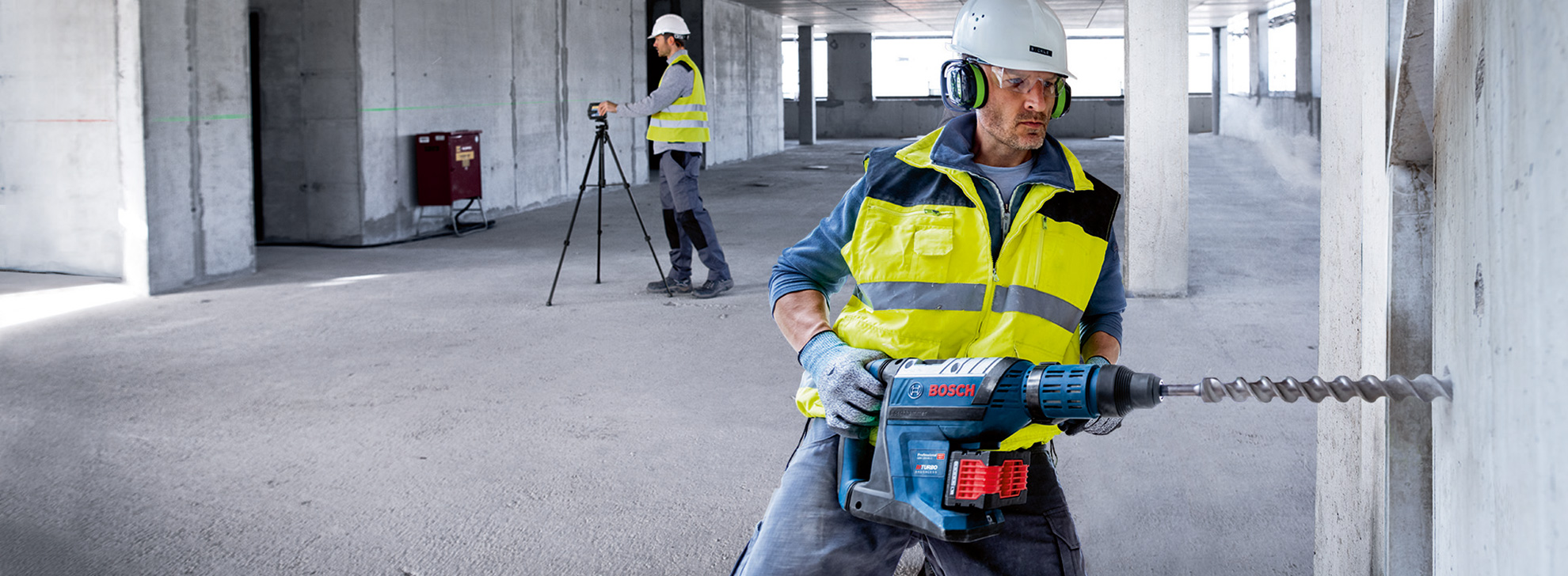 Строитель работает с дрелью Bosch на незавершенном строительстве.