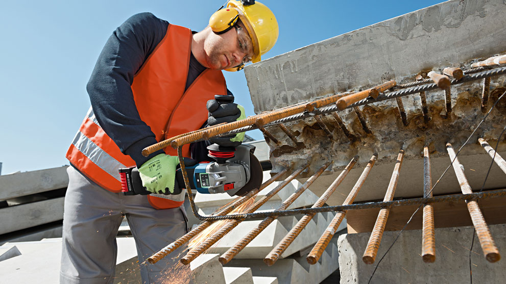 Рабочий в каске режет арматуру с помощью резака Bosch Professional.