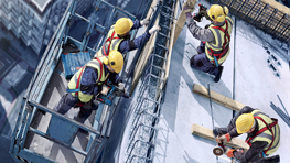 Чотири будівельники в шоломах працюють на риштуванні на будівельному майданчику.