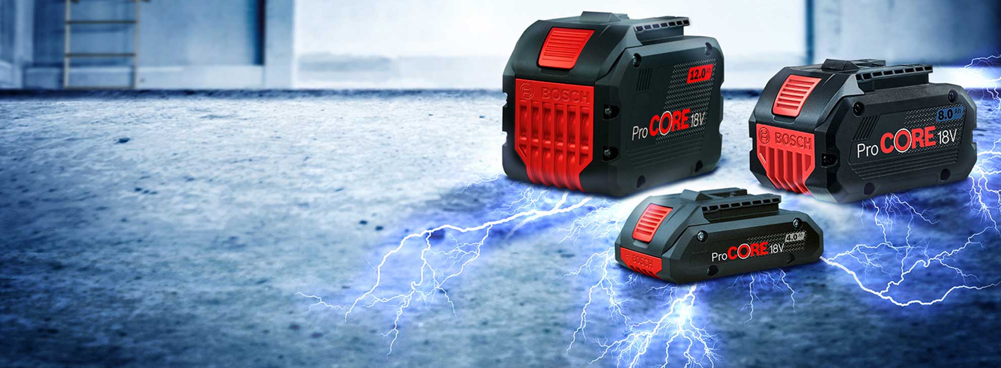 Três baterias Bosch ProCORE 18V em preto e vermelho sobre um chão cinza.