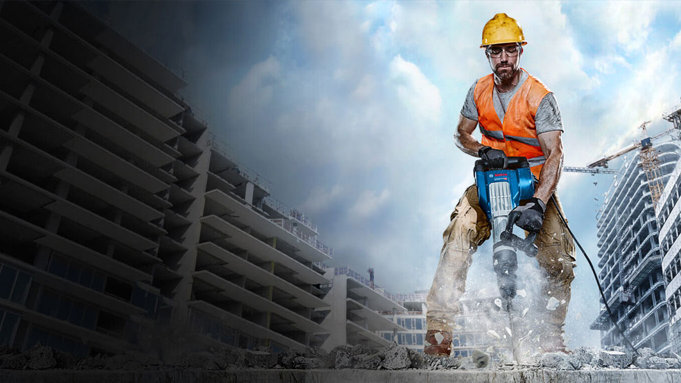 Čovek sa zaštitnom kacigom i narandžastim prslukom radi sa Bosch čekićem.