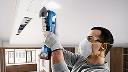 Ремесленник с инструментами Bosch отрезает потолок.