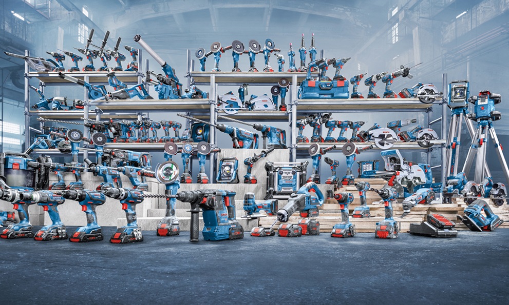 Různé modré nástroje Bosch Professional na policích a na podlaze.