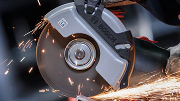 A Bosch Professional angle grinder cuts metal, sparks fly.