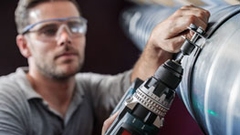 Un artisan portant des lunettes de protection utilise une perceuse noire Bosch.