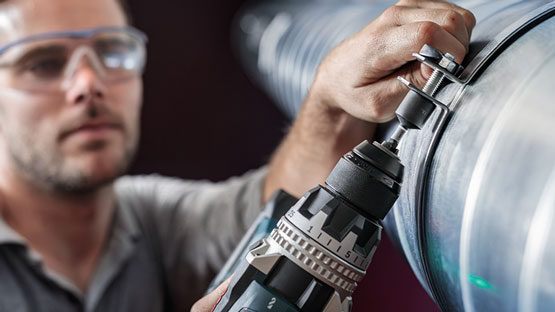 Un artisan utilise une perceuse sans fil Bosch Professional sur un tuyau.