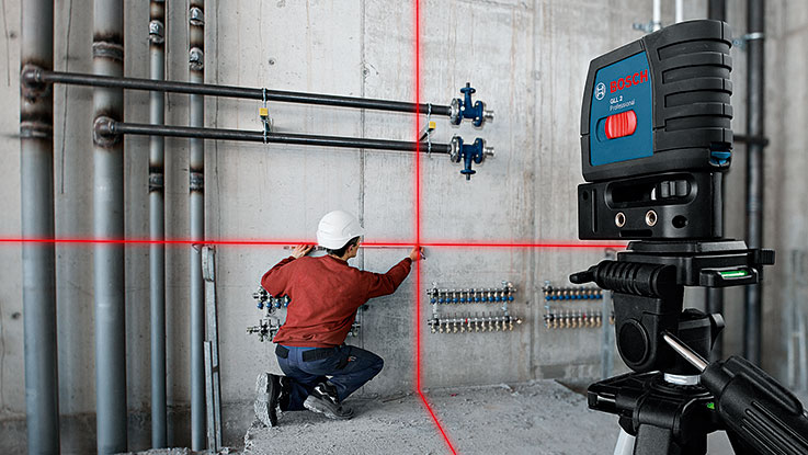 Un trabajador con casco utiliza un láser Bosch en una obra.