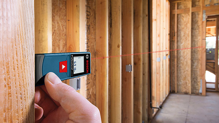 Un medidor de distancia láser Bosch Professional se sostiene contra una pared.