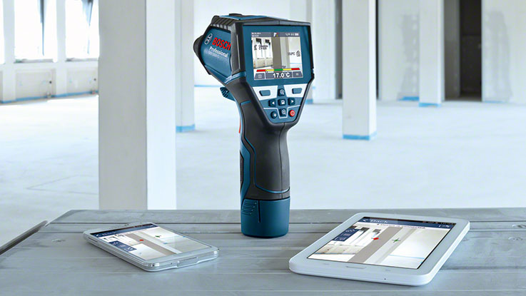 A Bosch Professional thermal imaging camera on a table with two tablets.