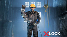 Мужчина в желтой каске держит инструмент Bosch X-LOCK в мастерской.