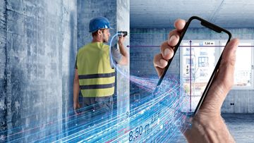 Een bouwvakker met een blauwe helm meet met een smartphone.