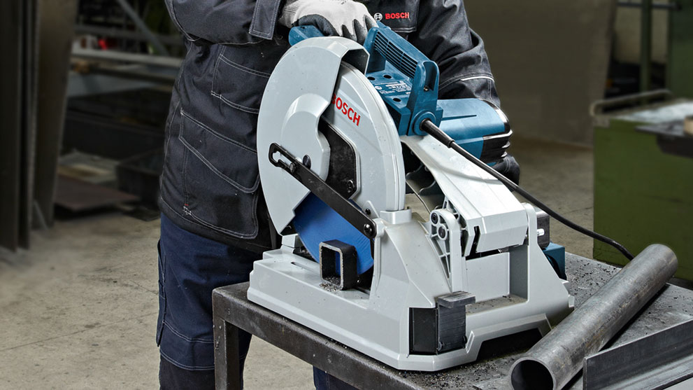 Профессиональная торцовочная пила Bosch стоит на столе, рабочий использует ее.