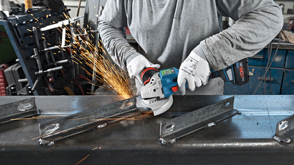 Рабочий режет металл синим угловым шлифовальным станком Bosch.