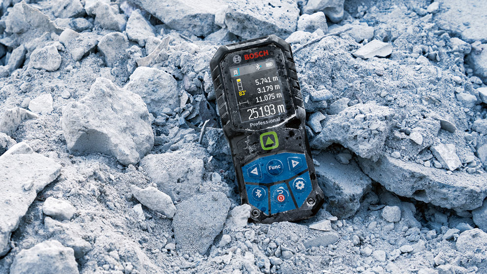 Un medidor de distancia Bosch Professional está sobre una roca gris.