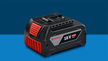 Черный аккумулятор Bosch Professional 18V лежит на синем фоне. Аккумулятор имеет красные и серые акценты.