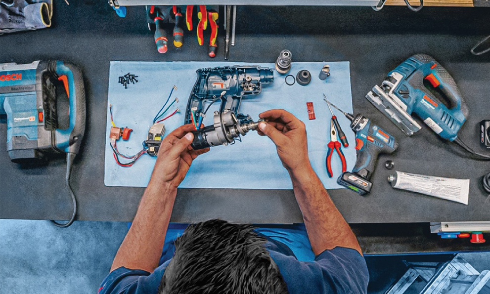A worker holds a Bosch Professional tool part over a table.