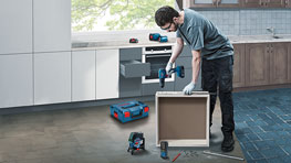 A craftsman is assembling a kitchen cabinet with Bosch tools.