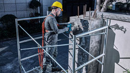 Pracovník s helmou používá nástroj Bosch na lešení.