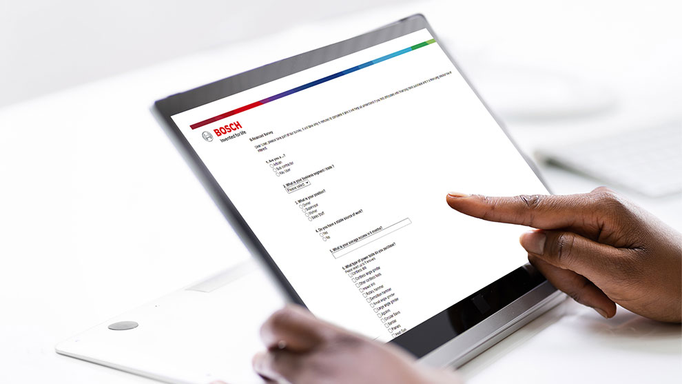 A person is using a tablet with a Bosch survey on the screen.