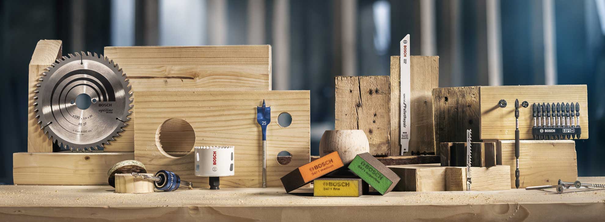 Профессиональные инструменты Bosch на деревянной доске: пильный диск, сверло, винты.