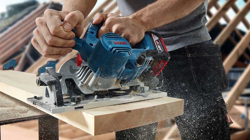 Профессиональная циркулярная пила Bosch режет дерево, пыль поднимается.