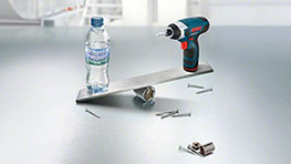 Аккумуляторная отвертка Bosch Professional, бутылка с водой и винты на металле.