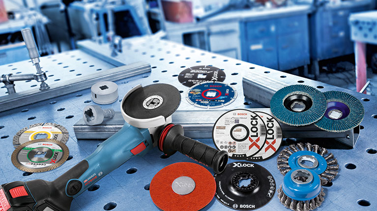 Úhlová bruska Bosch Professional s příslušenstvím na pracovní desce.
