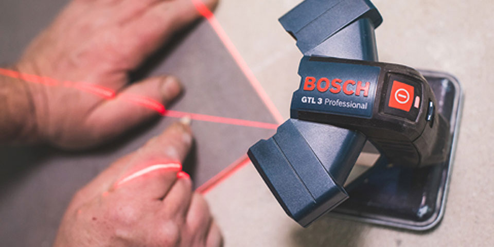 Laserové zařízení Bosch Professional vyzařuje červené čáry na povrch.