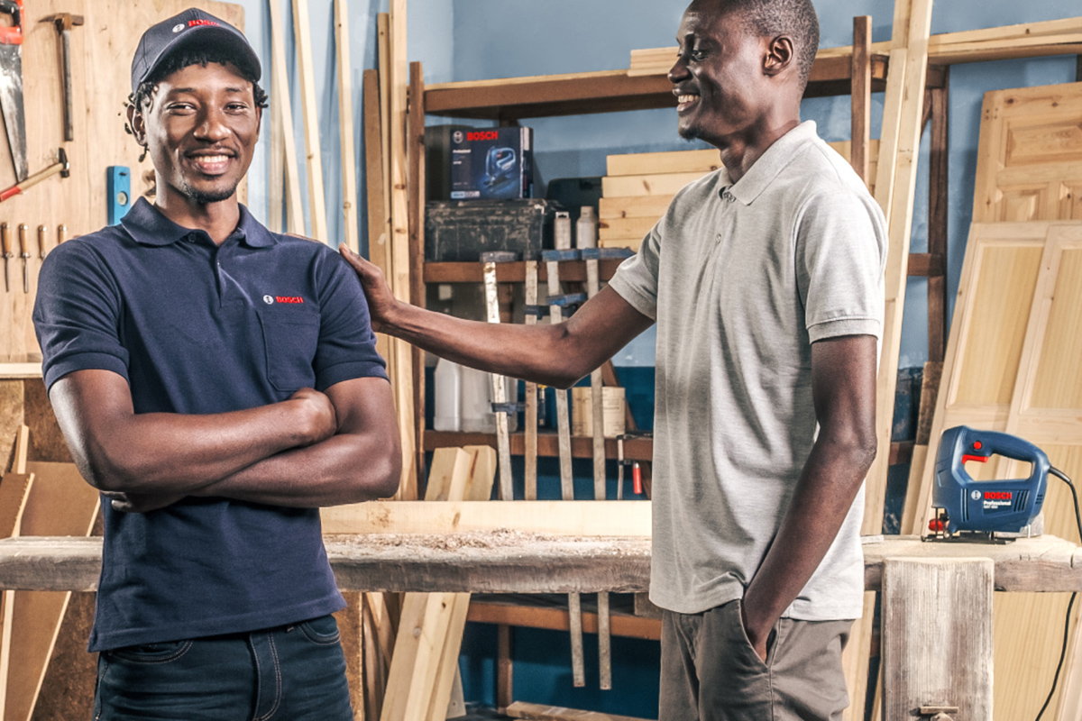 Two men stand in a workshop, Bosch tools in the background.