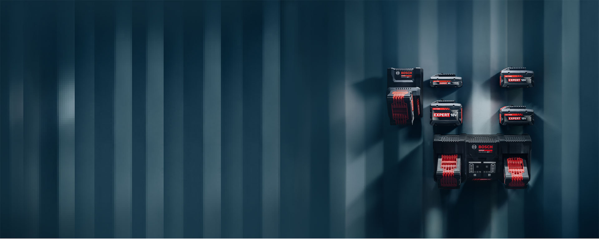 Различные аккумуляторы Bosch Professional, установленные на синей стене.