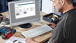 Un hombre en la computadora, rodeado de herramientas y accesorios Bosch.