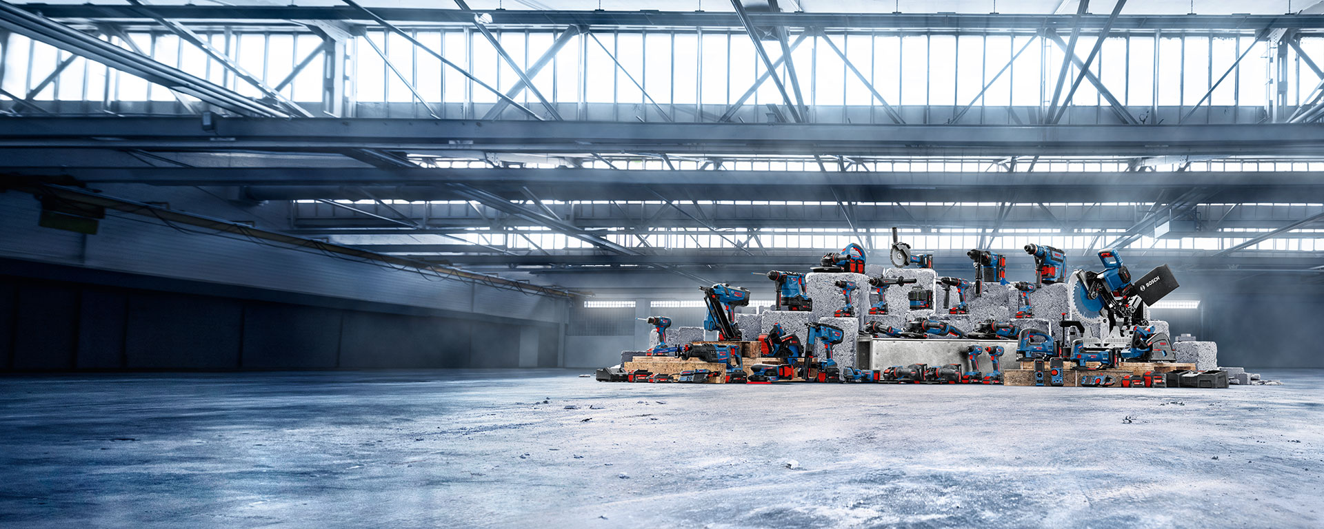 Skladovací prostor s několika modrými a červenými nástroji uspořádanými na šedých betonových dílech.