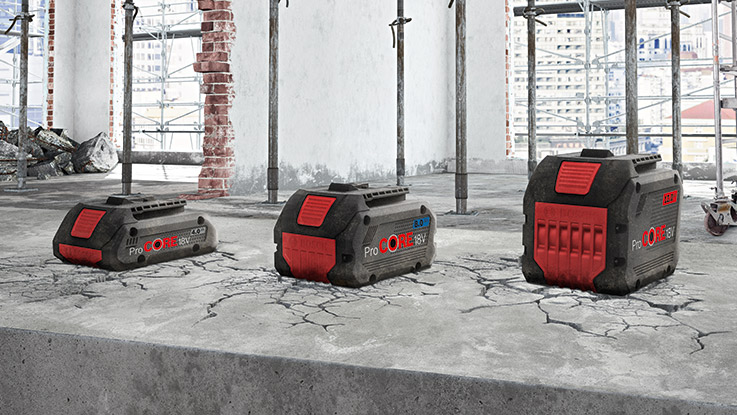 Tre Bosch Professional batteripaket på sprucken betonggolv på byggarbetsplats.