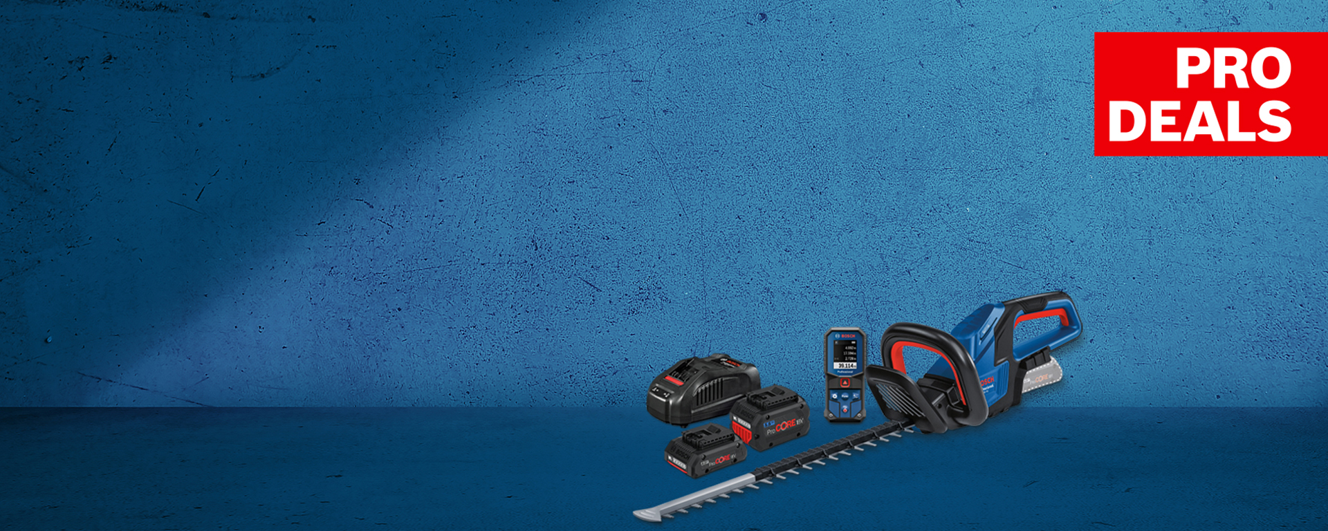 Un tagliasiepi a batteria Bosch Professional in blu, accanto a due batterie e un caricabatterie su una superficie blu.