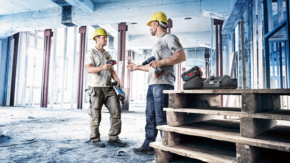 Twee bouwvakkers met Bosch-gereedschap staan op een houten pallet.