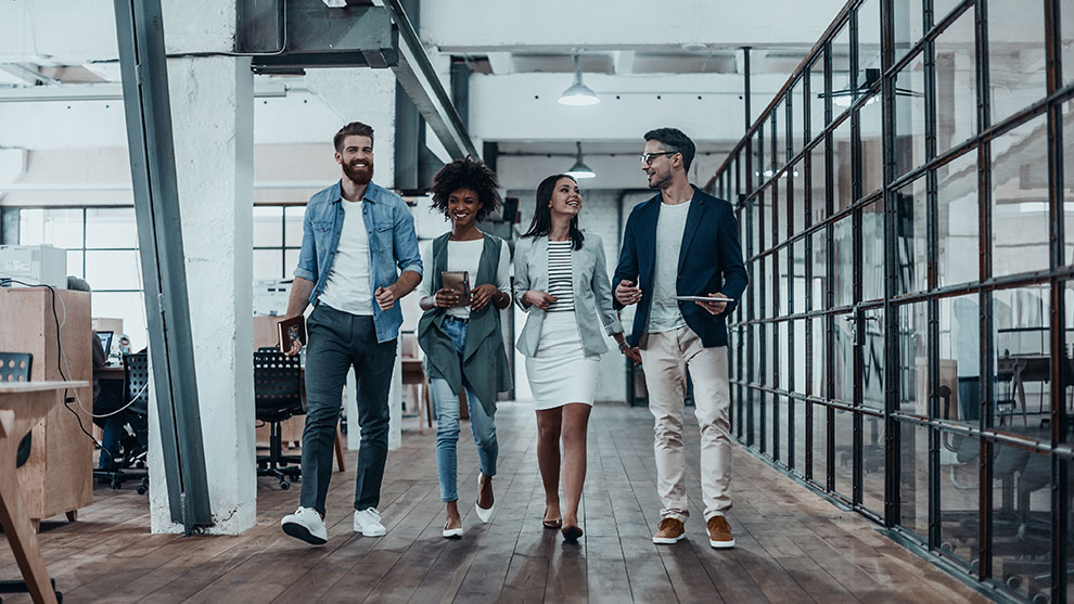 Fyra personer går tillsammans i ett modernt kontor.