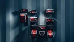 En una pared azul cuelgan varias herramientas rojas y baterías de diferentes tamaños.