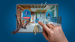 Una mano toca una pantalla que muestra un proyecto de artesanía virtual. La habitación tiene características de obra, con herramientas y materiales visibles. En la pantalla son visibles los símbolos de 'Experto' y 'Pro'.