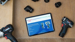 Una tableta muestra un resumen técnico, rodeada de varias herramientas y accesorios.