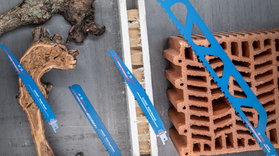 Blaue Bosch Professional Sägen liegen neben Holz und Ziegelsteinen.