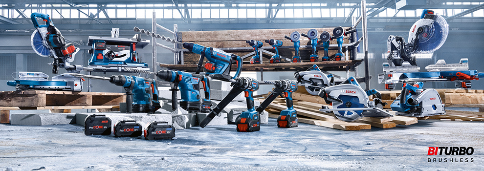 Forskellige blå Bosch Professional værktøjer på træbjælker og gulv.