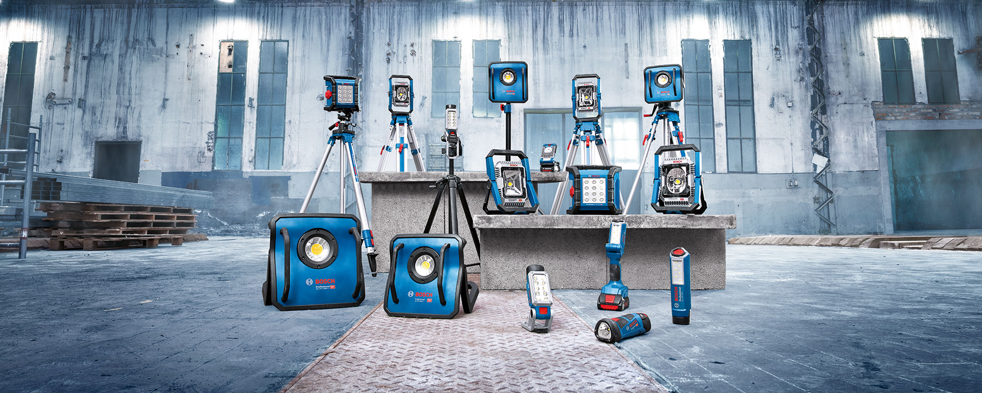 Plusieurs lampes de chantier Bosch Professional bleues sont posées sur un bloc en béton.