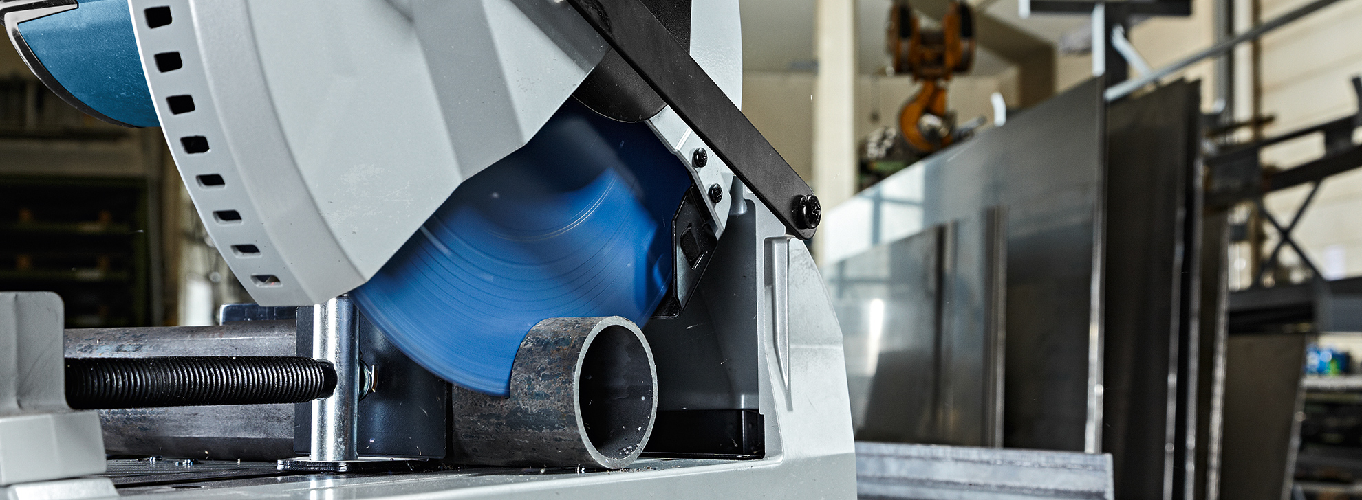 A Bosch Professional table saw with a blue saw blade and a metal tube in focus, background blurred.
