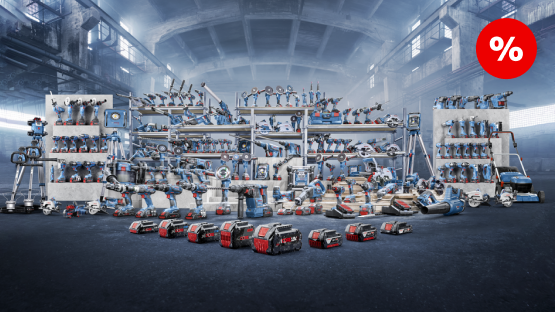 A variety of hand tools are displayed on shelves in a large, well-lit hall. Tools in various sizes and colors, predominantly blue and red, are neatly arranged. In the foreground, numerous batteries and devices are placed, while shelves with additional tools are visible in the background. The atmosphere feels industrial and well-organized, with a discount sign in the upper right corner.