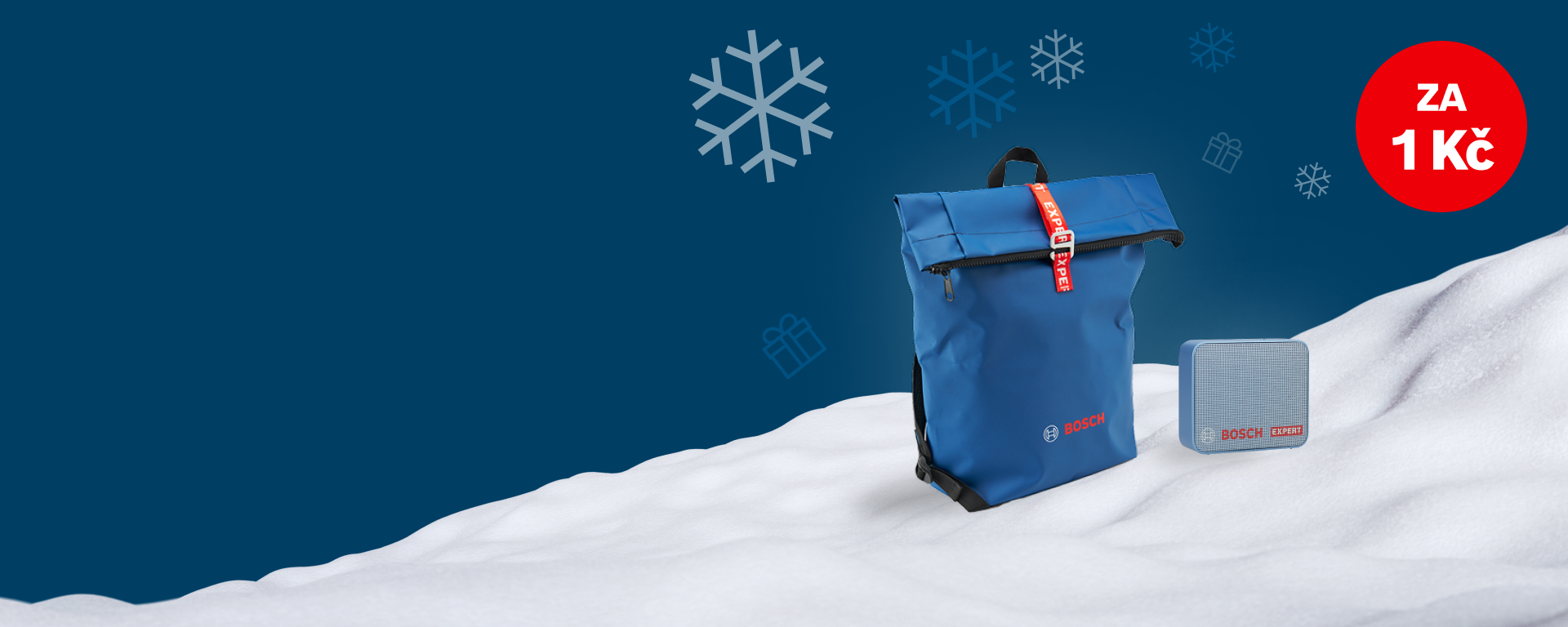 Modrý batoh a reproduktor na zasněženém povrchu, zimní atmosféra.