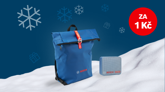 Modrý batoh a šedá krabice na sněhově bílé ploše, zimní atmosféra se sněhovými vločkami.