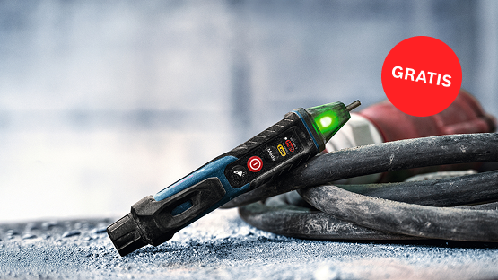 Un comprobador de voltaje Bosch Professional con luz verde está sobre una superficie rugosa, rodeado de cables. Una etiqueta roja de 'GRATIS' es visible.