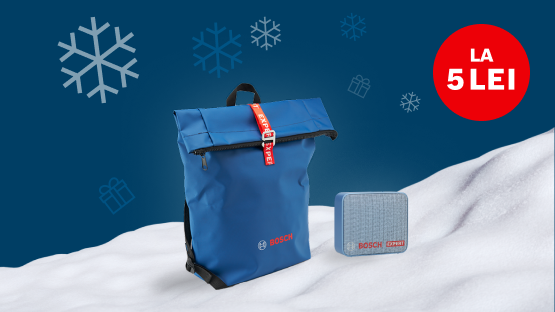 Un rucsac albastru și o cutie gri pe o suprafață acoperită cu zăpadă, fundal albastru.