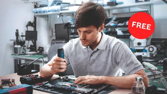 A young man with a blue tool in hand is working intently on a circuit board on a table. In the background, various tools and devices are visible, while a red "FREE" label is prominently placed in the corner. The room appears modern and well-lit, creating a productive atmosphere.