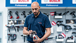 Un homme avec une barbe tient un outil Bosch Professional dans la main.